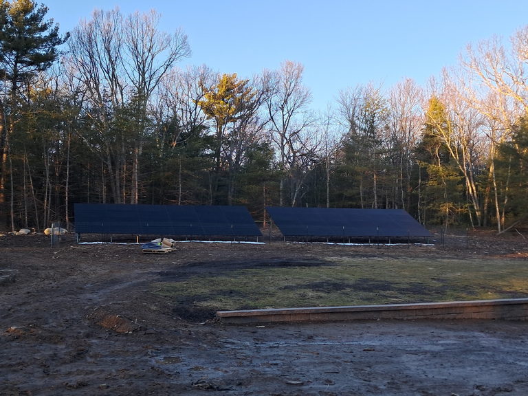 A ground-mounted solar array in a cleared yard